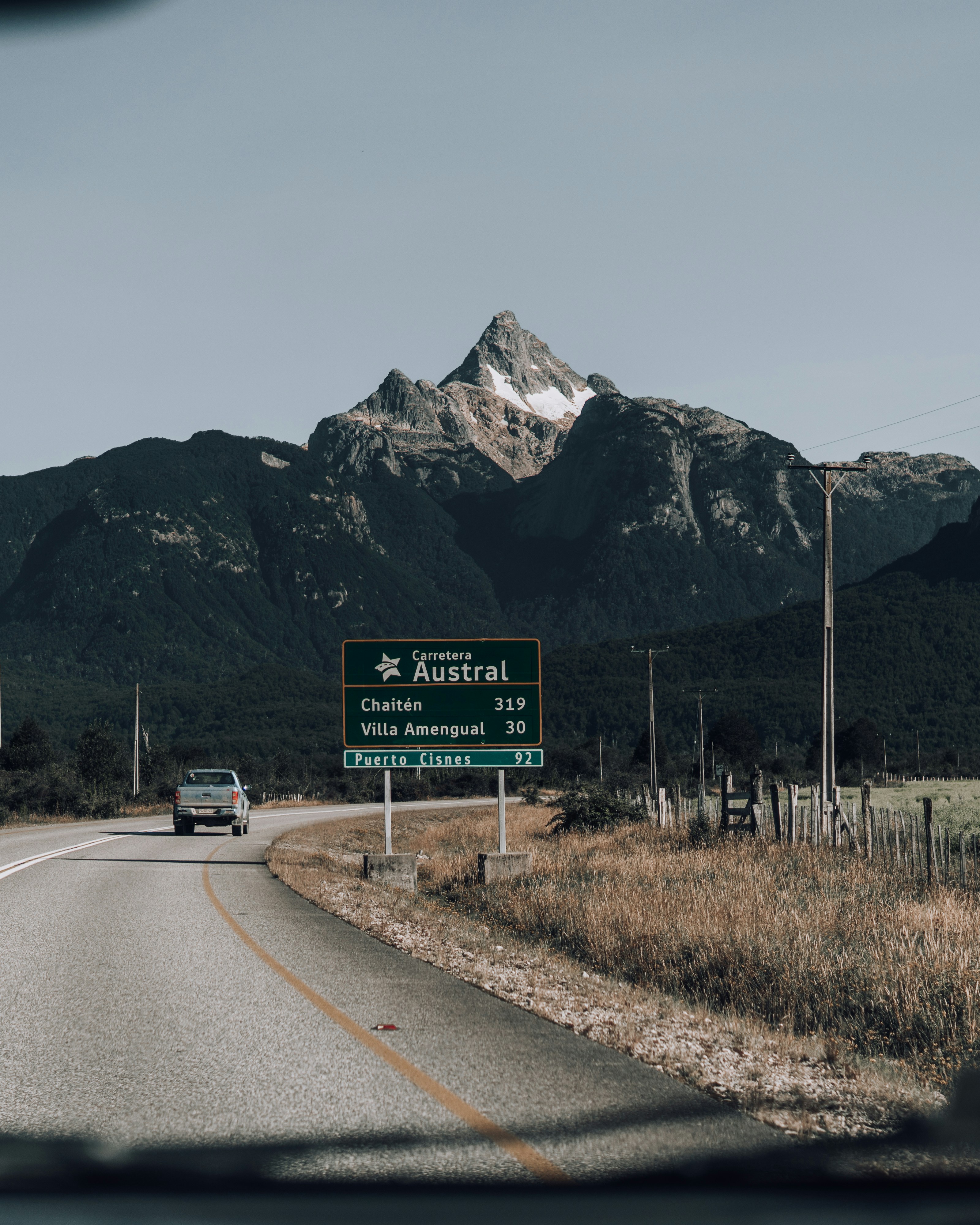 A car driving down a road with a mountain in the background