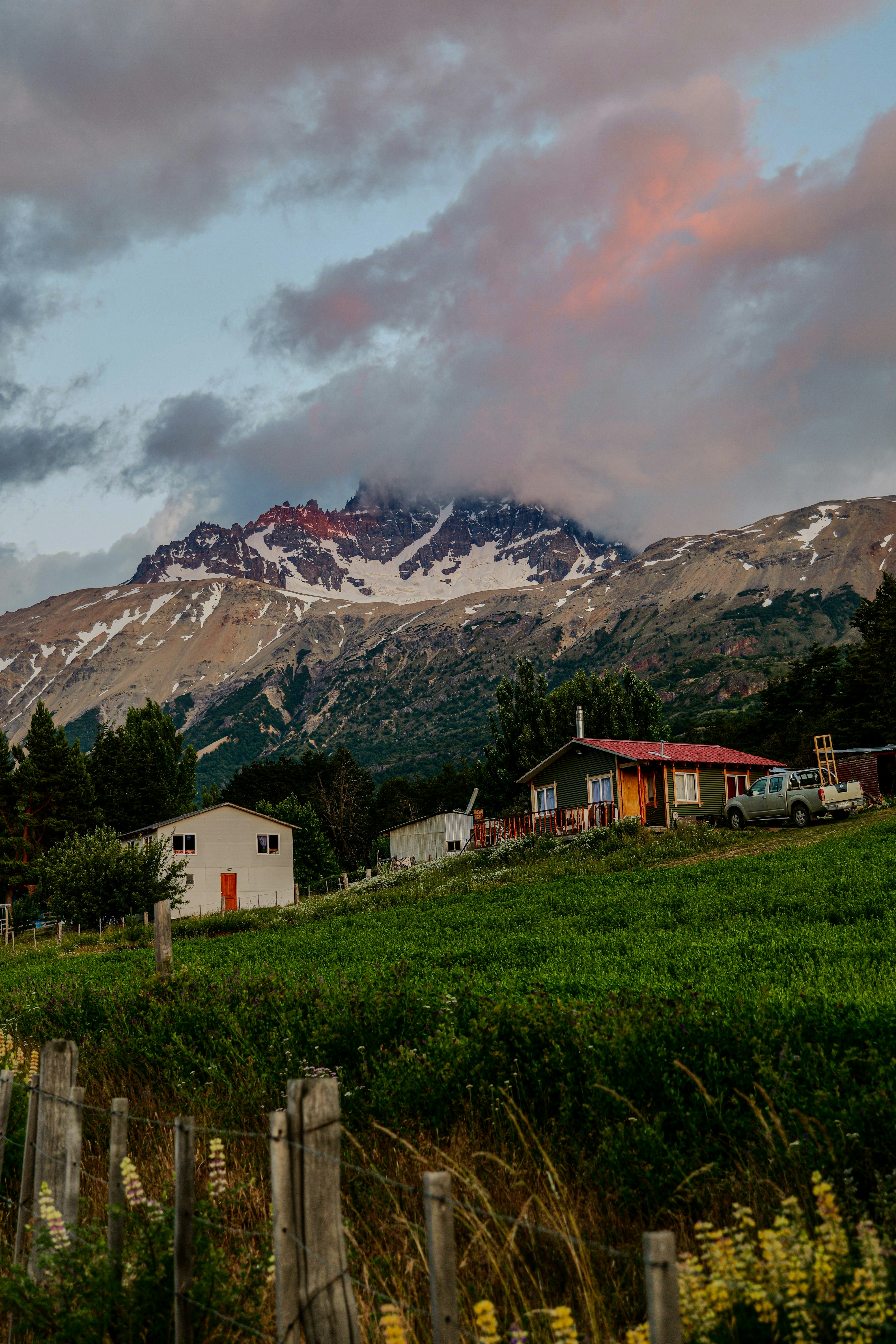 A field with a house and mountains in the background